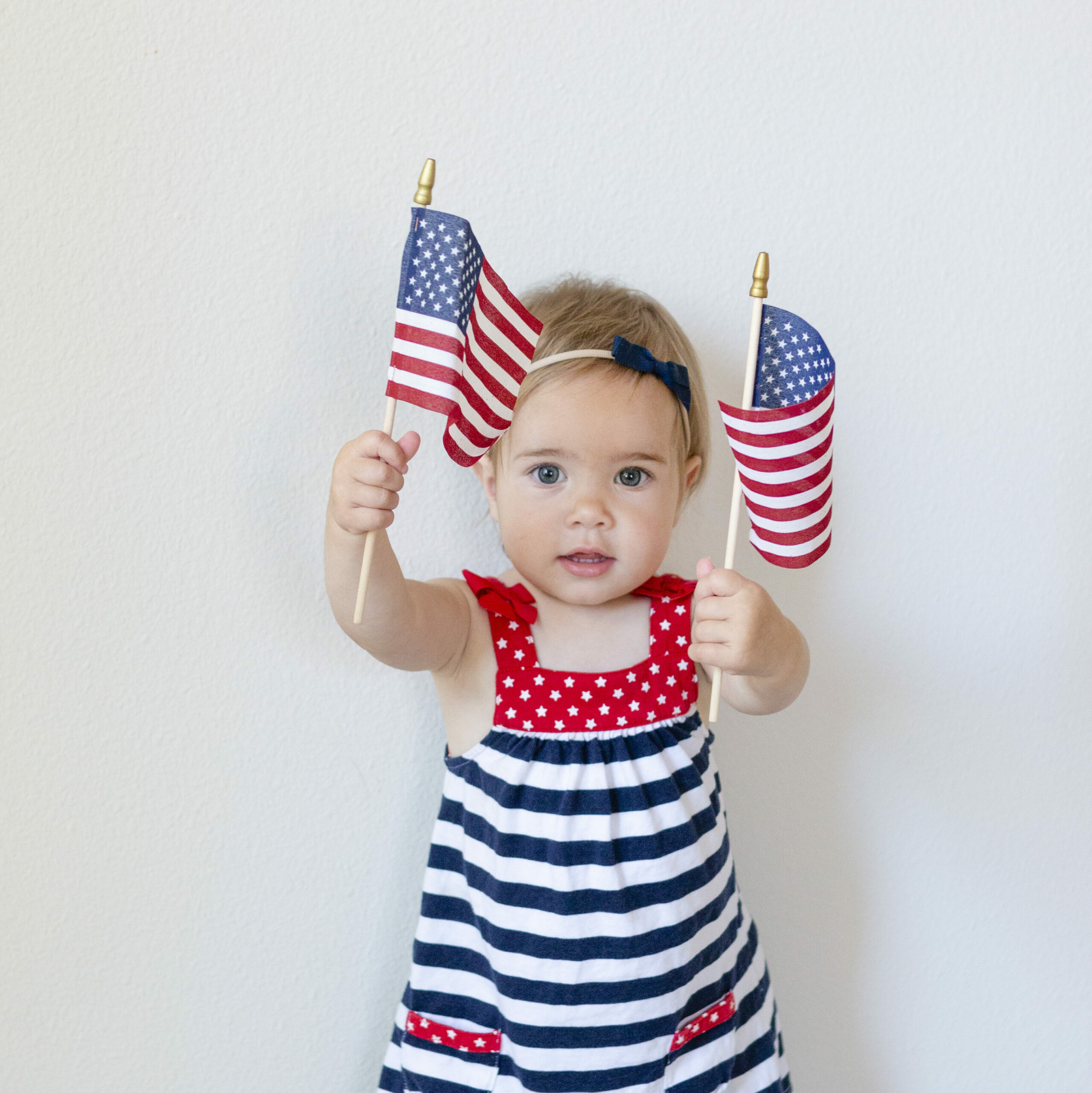 Toddler girl holding American flags