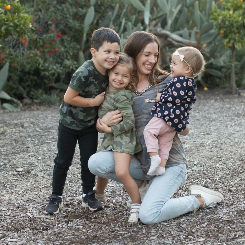 Mom kneeling outdoors with her three kids