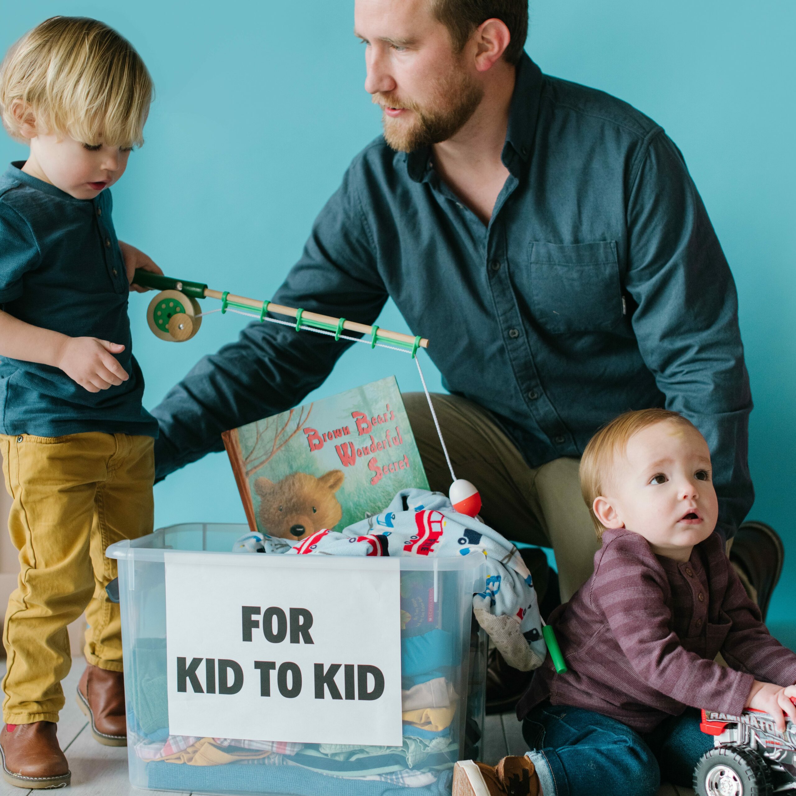 boys and their father with a box of donation items for Kid to Kid