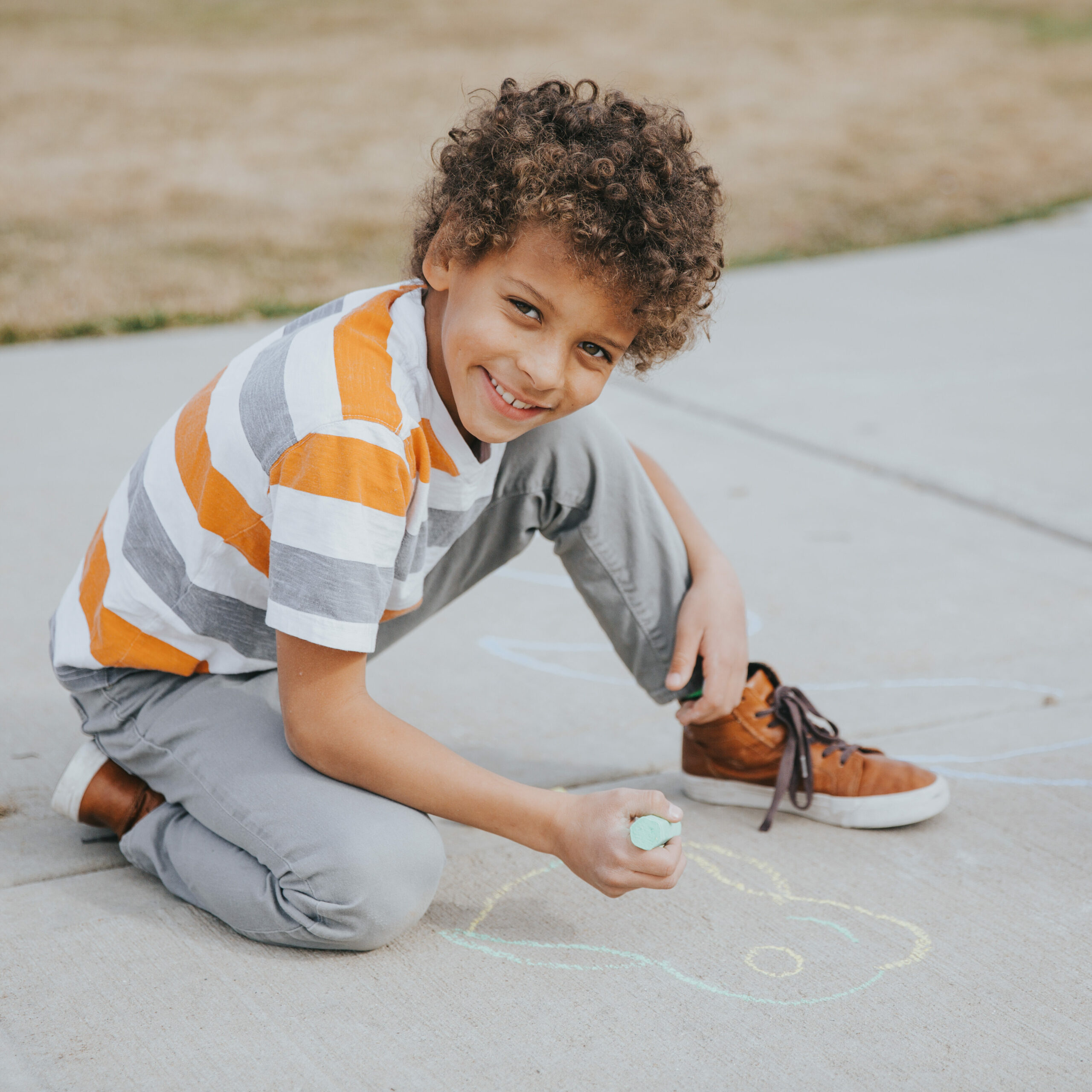 boy coloring on the sidewalk