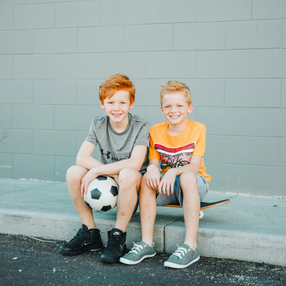 boys sitting on sidewalk with soccer ball