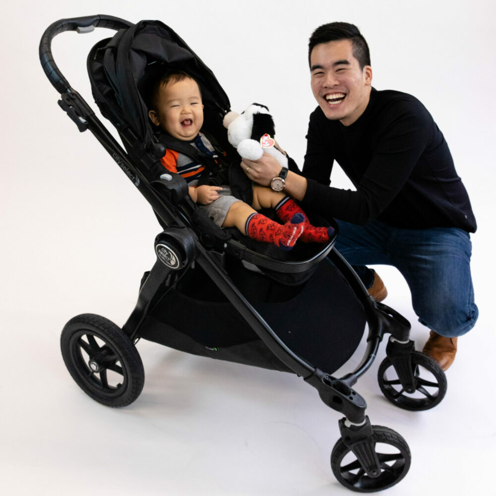 Father giving toy to his son in an umbrella stroller